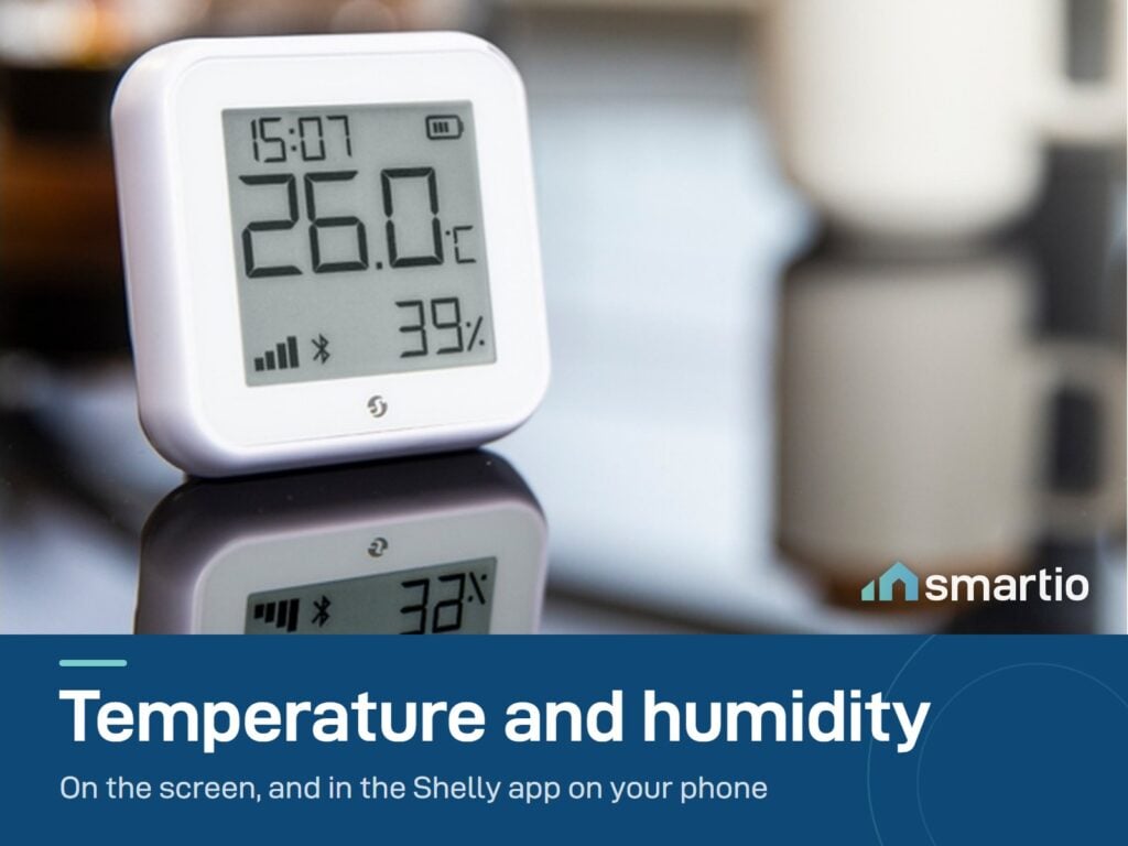 Shelly H&T Gen3 sensor on a desk showing 26 degrees and 39 percent humidity on its e-paper screen